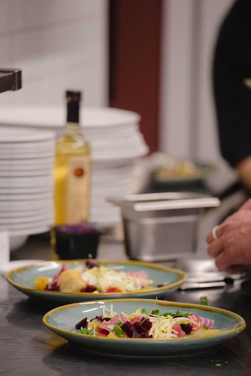 Essen wird in der Kantine angerichtet für das Catering, zwei Teller stehen auf dem Tisch mit essen drauf